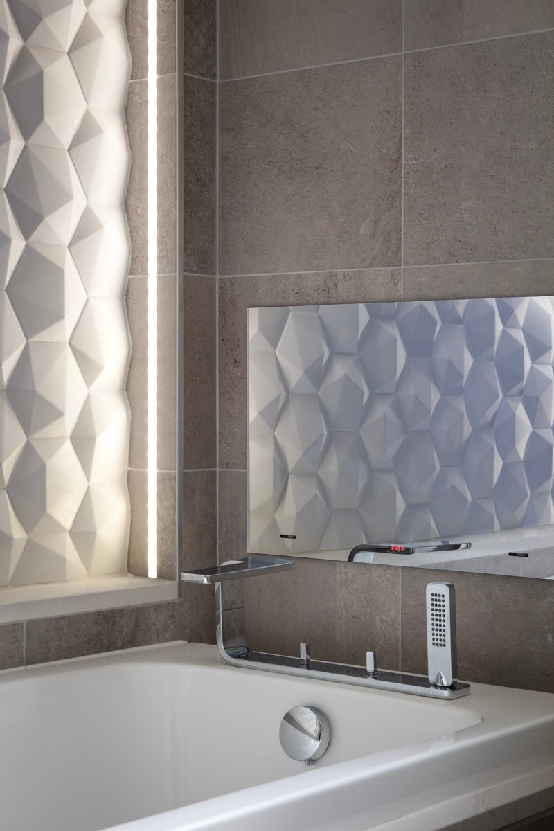 Deck-mounted bath filler and hand shower in front of a lit 3D tile panel, in Lisa Hensby's own bathroom