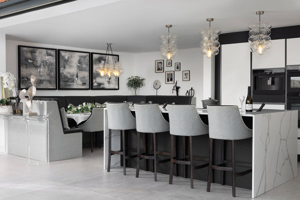 Open plan kitchen diner with marble-effect island, upholstered bar stools, bespoke banquette dining booth, bubble glass pendant lights and large format floor tiles. Designed by Lisa Hensby Design & Build Studio.