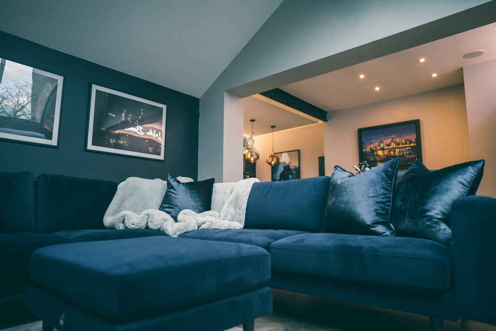 Navy velvet corner sofa in the living end of the kitchen extension, with the kitchen and pendants beyond