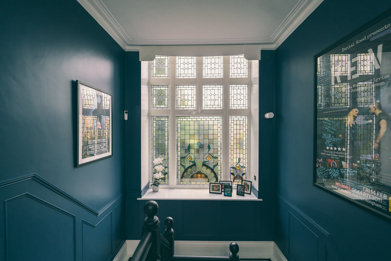 Navy panelled landing with a leaded stained-glass window in a Manchester home by Lisa Hensby Design & Build Studio