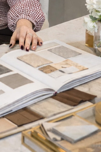  An open sample book with fabric and material swatches is open on a desk.