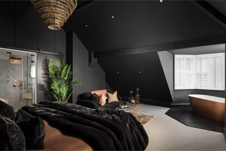 A luxury master bedroom suite featuring charcoal walls, freestanding copper bathtub, velvet bedding, copper shower fixtures and a tiered chandelier - designed by Lisa Hensby Design & Build Studio
